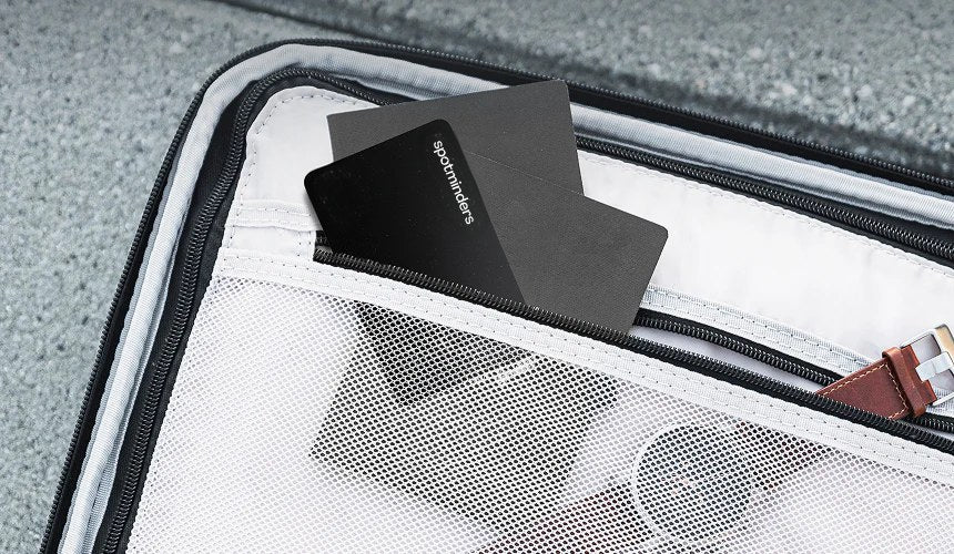 A Spotminders card slipped into the lining pocket of an open suitcase