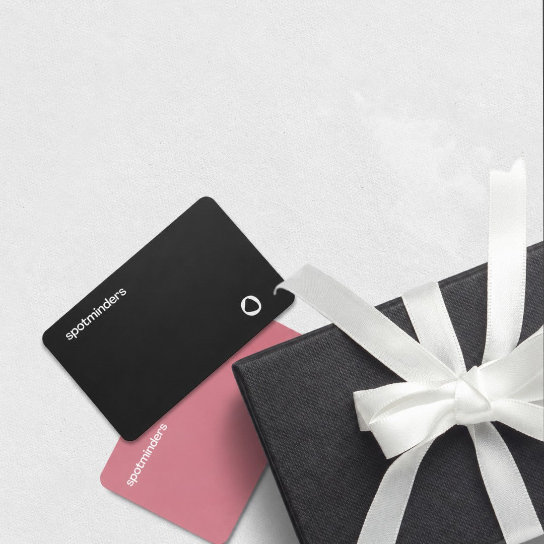 A black and a pink Spotminders tracking card beside a gift box with a white ribbon