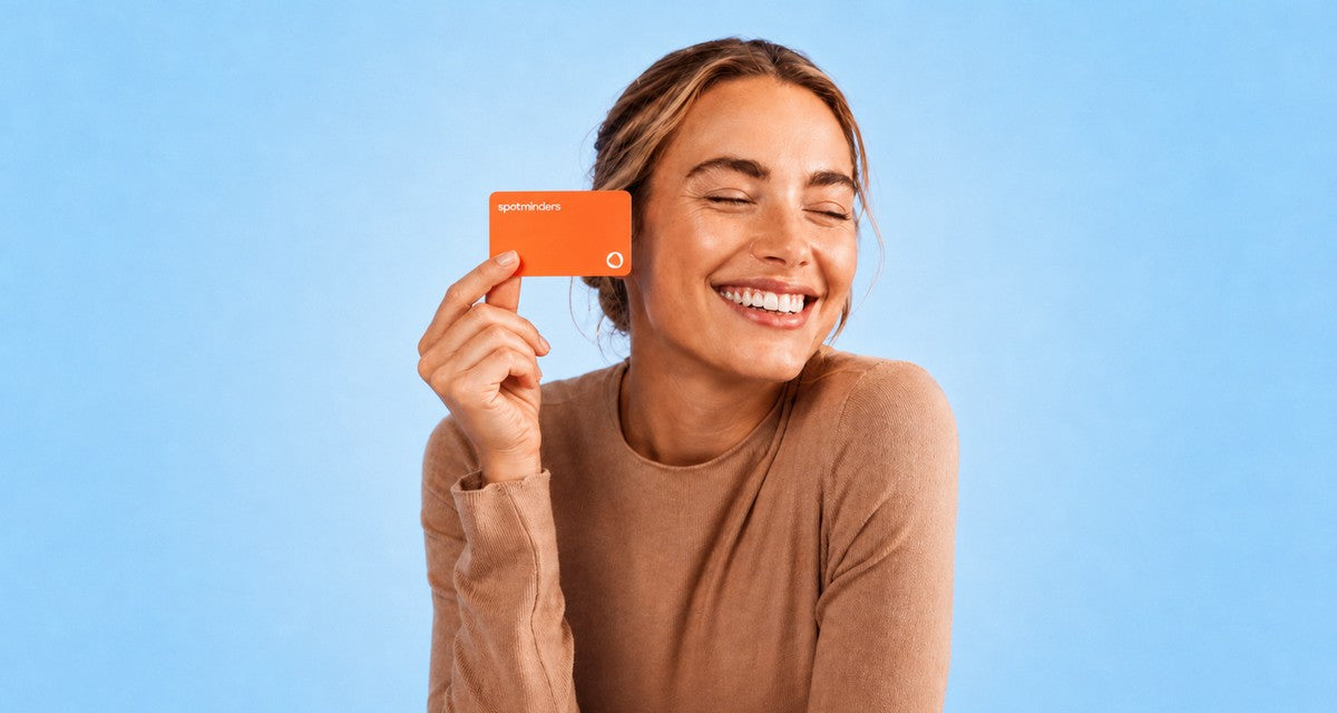 A smiling woman holding a Spotminders tracking card