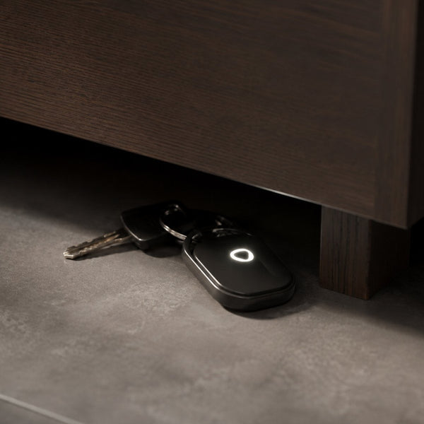Smart Tag LED glowing on a set of keys under a cabinet